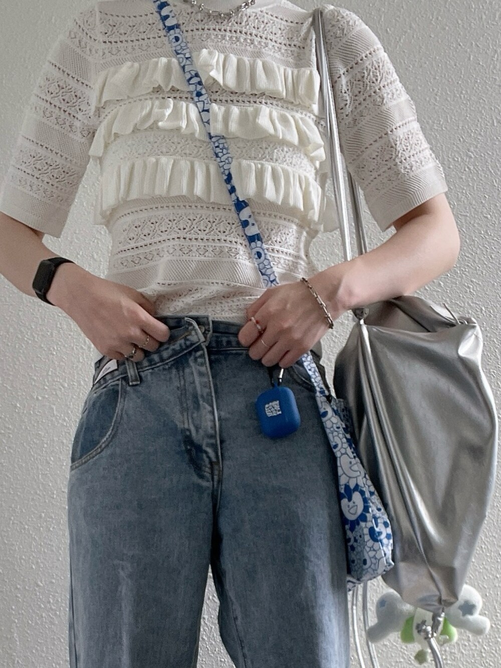 ホワイト系のニット/セーター、シルバー系のバックパック/リュック、ブルー系のデニムパンツを着用したレディースの夏コーディネートの3枚目の写真