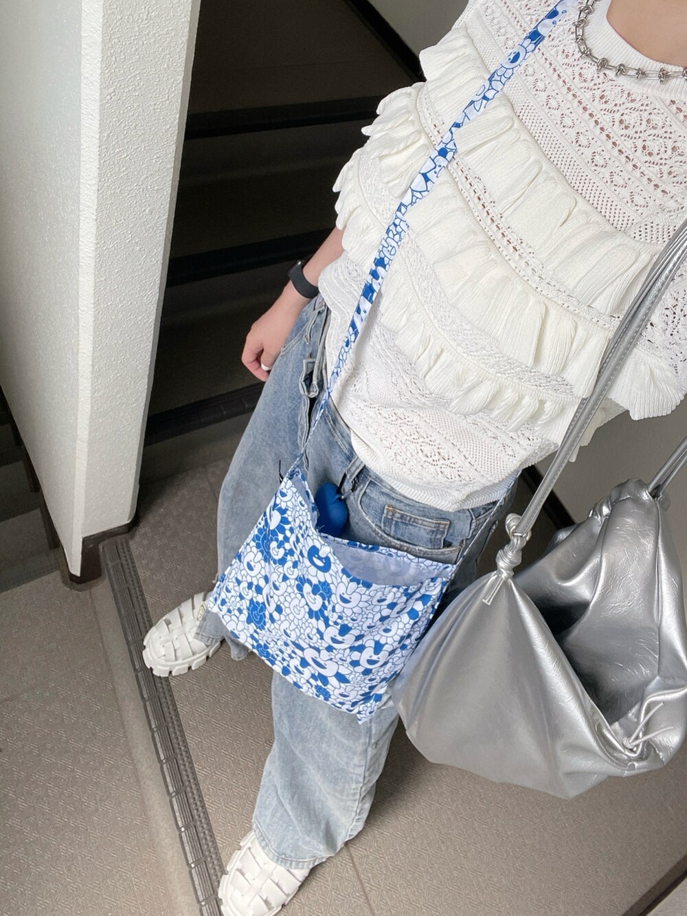 ホワイト系のニット/セーター、シルバー系のバックパック/リュック、ブルー系のデニムパンツを着用したレディースの夏コーディネートの2枚目の写真