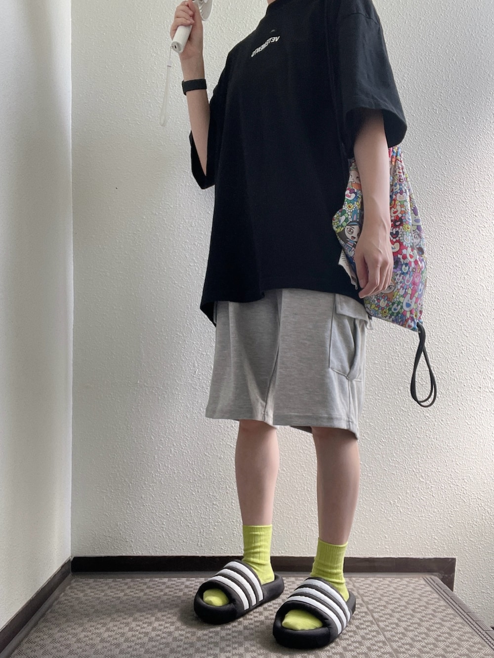 ブラック系のTシャツ/カットソー、グレー系のパンツ、ブラック系のサンダルを着用したレディースの秋コーディネートの2枚目の写真