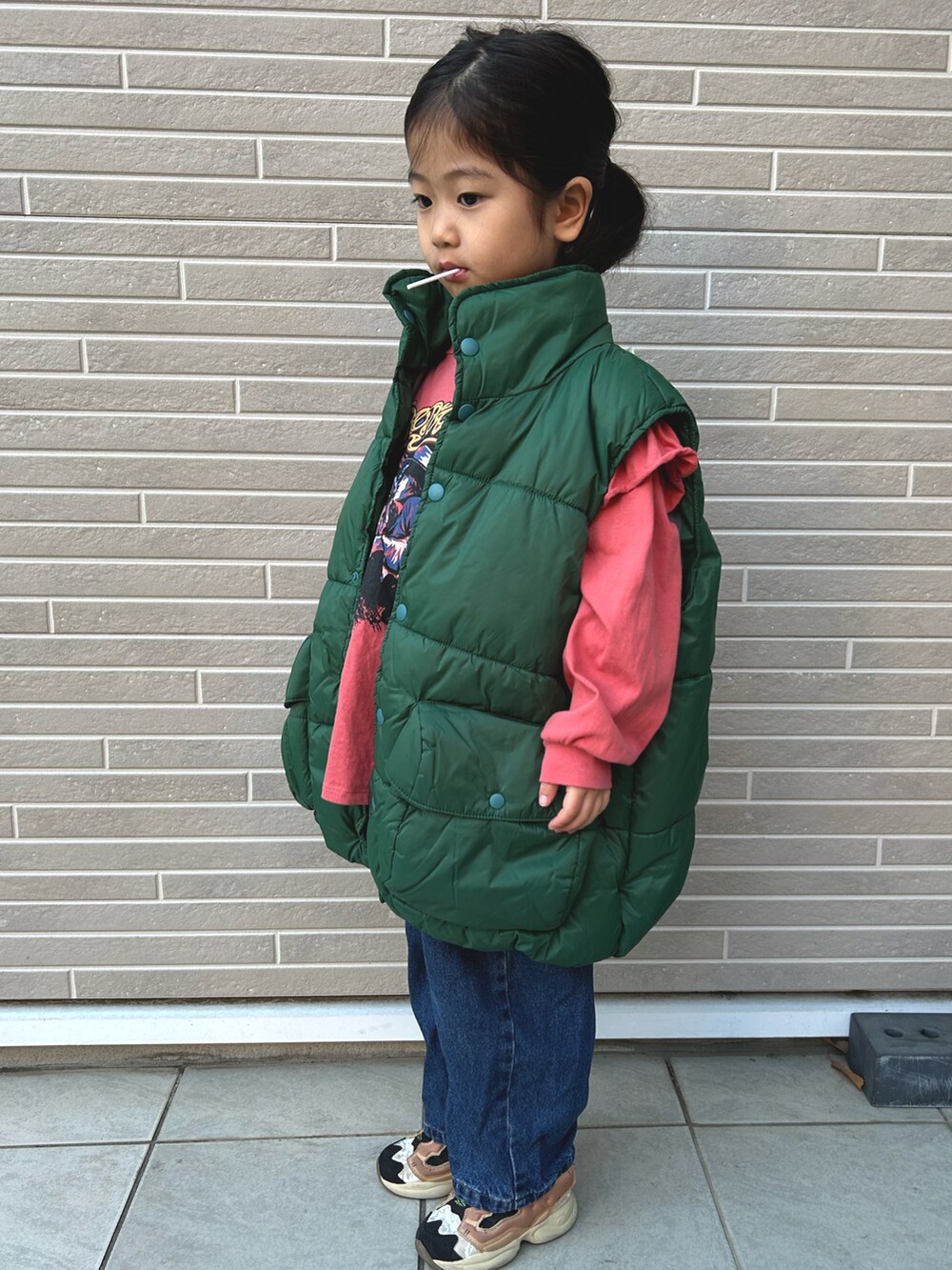 グリーン系のダウンベスト、ピンク系のTシャツ/カットソーを着用したキッズの冬コーディネートの2枚目の写真