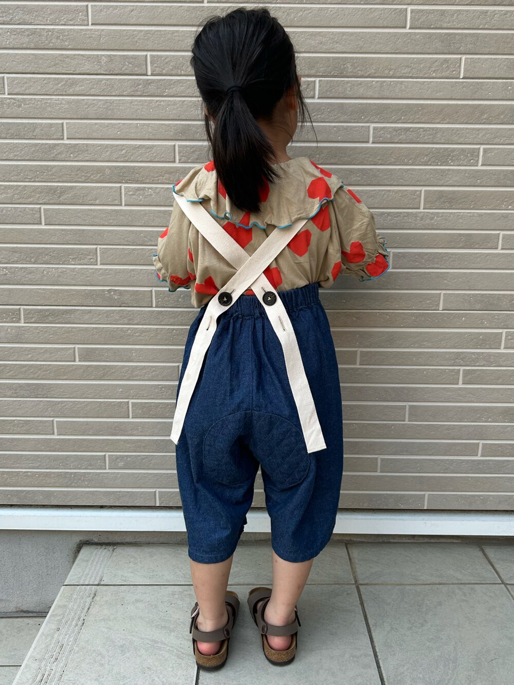 ブルー系のパンツ、ブラウン系のサンダル、オレンジ系のTシャツ/カットソーを着用したキッズの夏コーディネートの2枚目の写真