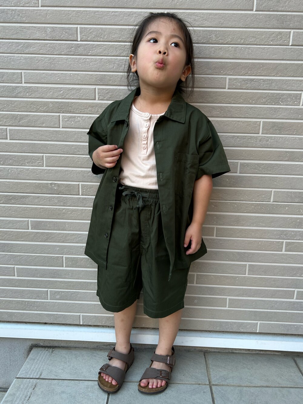 ブラウン系のサンダル、ブラック系のセットアップを着用したキッズの夏コーディネートの2枚目の写真