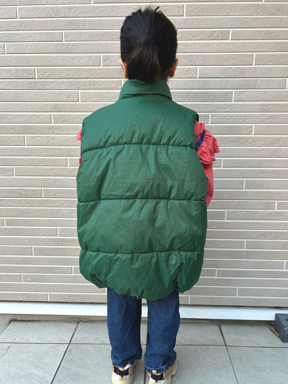 グリーン系のダウンベスト、ピンク系のTシャツ/カットソーを着用したキッズの冬コーディネートの3枚目の写真