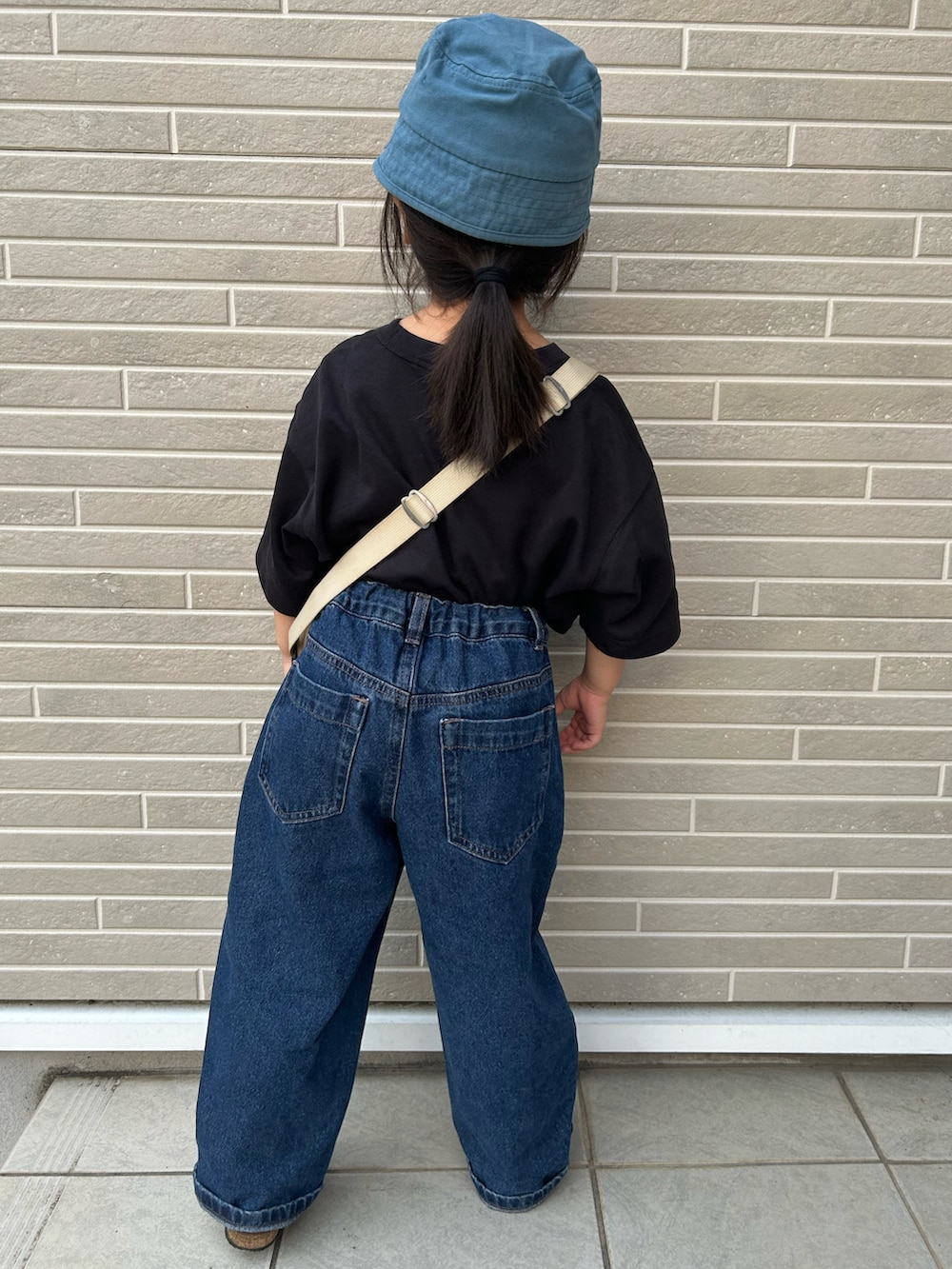 ブラック系のTシャツ/カットソー、ブラウン系のショルダーバッグ、ブルー系のデニムパンツを着用したキッズの夏コーディネートの3枚目の写真