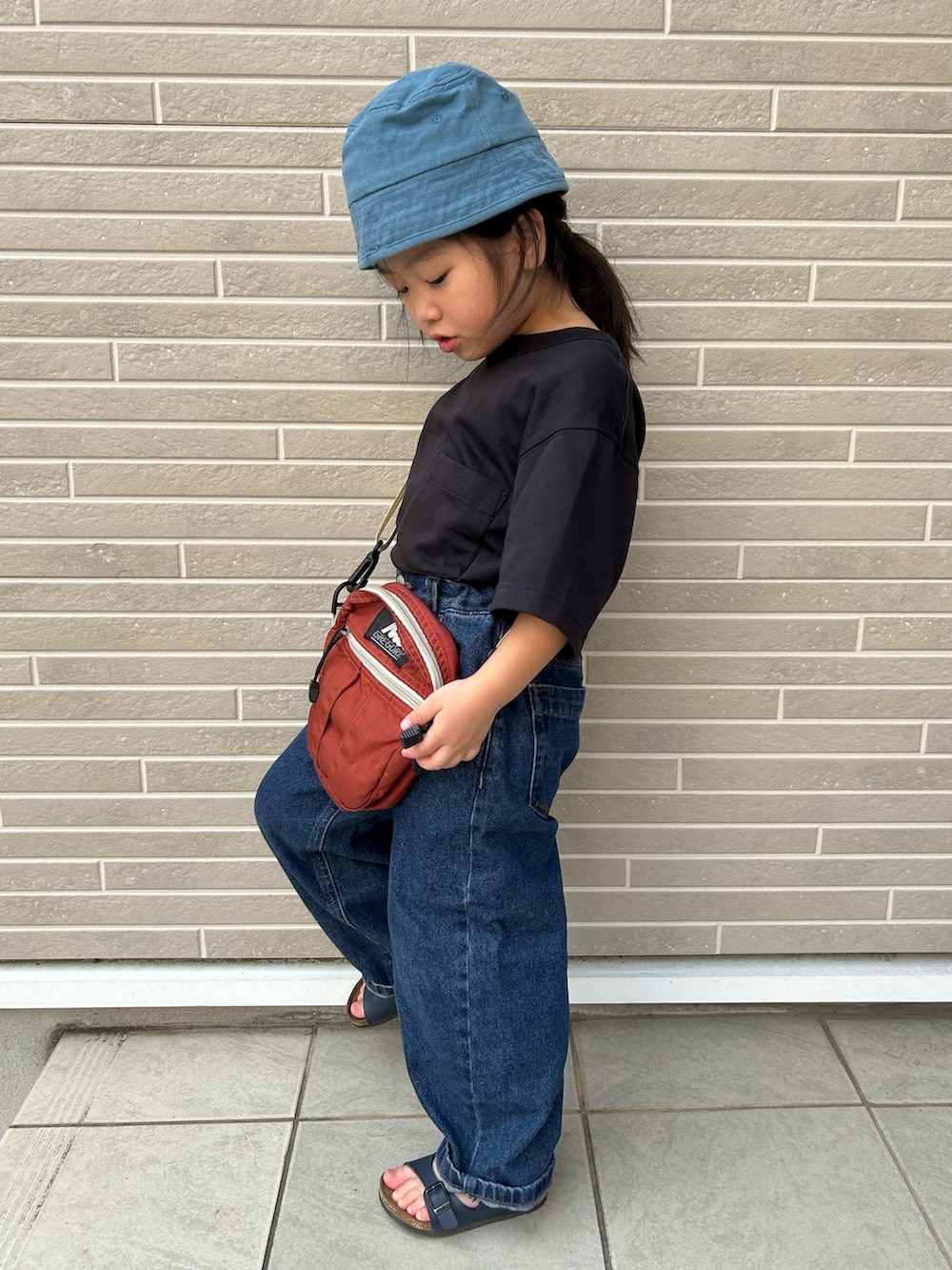 ブラック系のTシャツ/カットソー、ブラウン系のショルダーバッグ、ブルー系のデニムパンツを着用したキッズの夏コーディネートの2枚目の写真