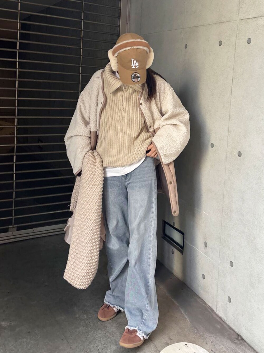 ベージュ系のニット/セーター、ホワイト系のTシャツ/カットソー、ブルー系のデニムパンツを着用したレディースの冬コーディネートの2枚目の写真