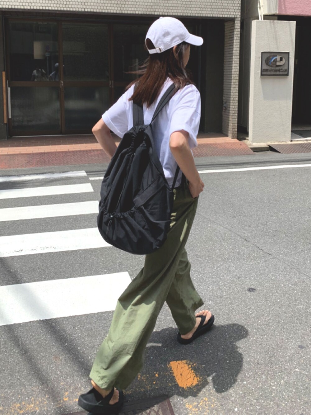 ホワイト系のTシャツ/カットソー、グリーン系のスラックス、ブラック系のバックパック/リュックを着用したレディースの夏コーディネートの2枚目の写真