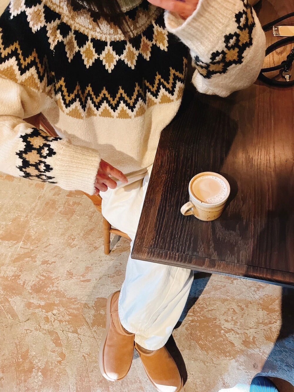 ベージュ系のムートンコート、ホワイト系のニット/セーター、ホワイト系のTシャツ/カットソーを着用したレディースの冬コーディネートの2枚目の写真