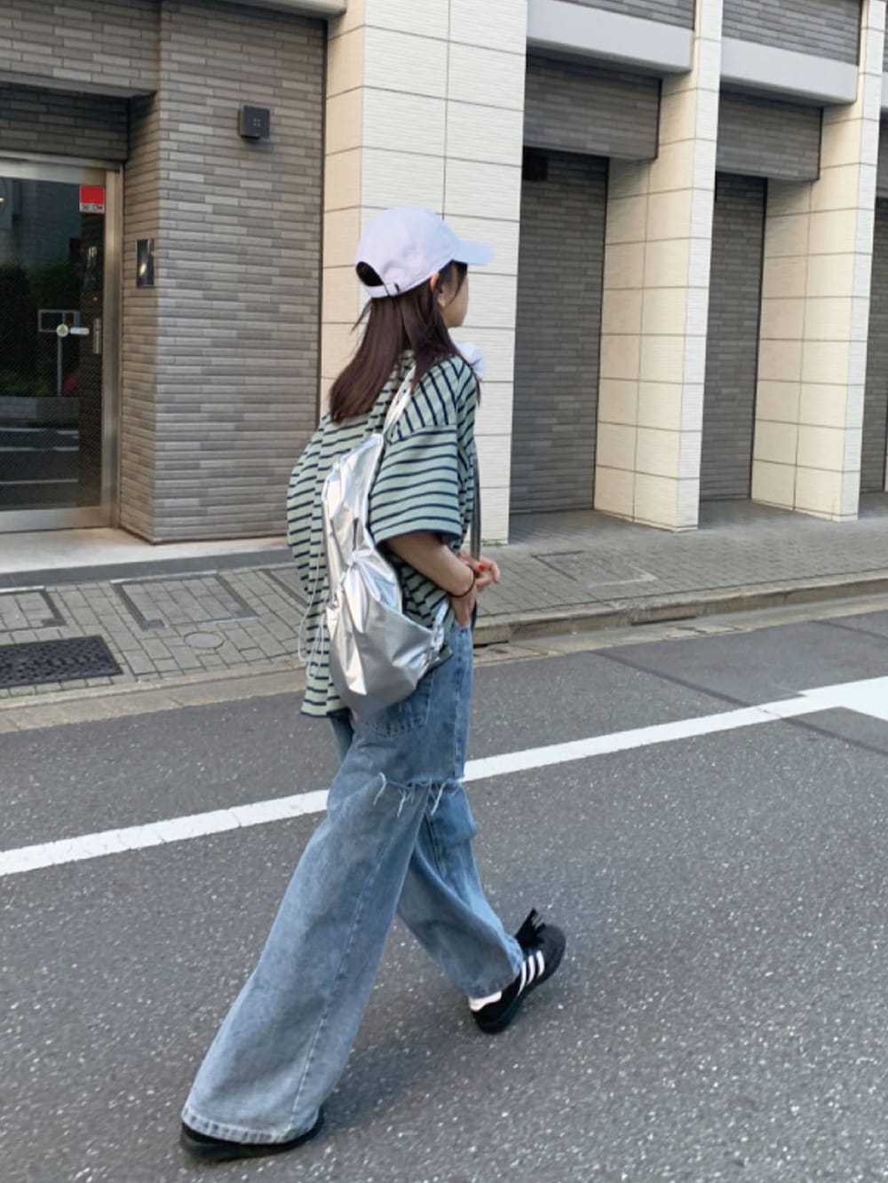 グリーン系のTシャツ/カットソー、シルバー系のバックパック/リュック、ブルー系のデニムパンツを着用したレディースの春コーディネートの2枚目の写真