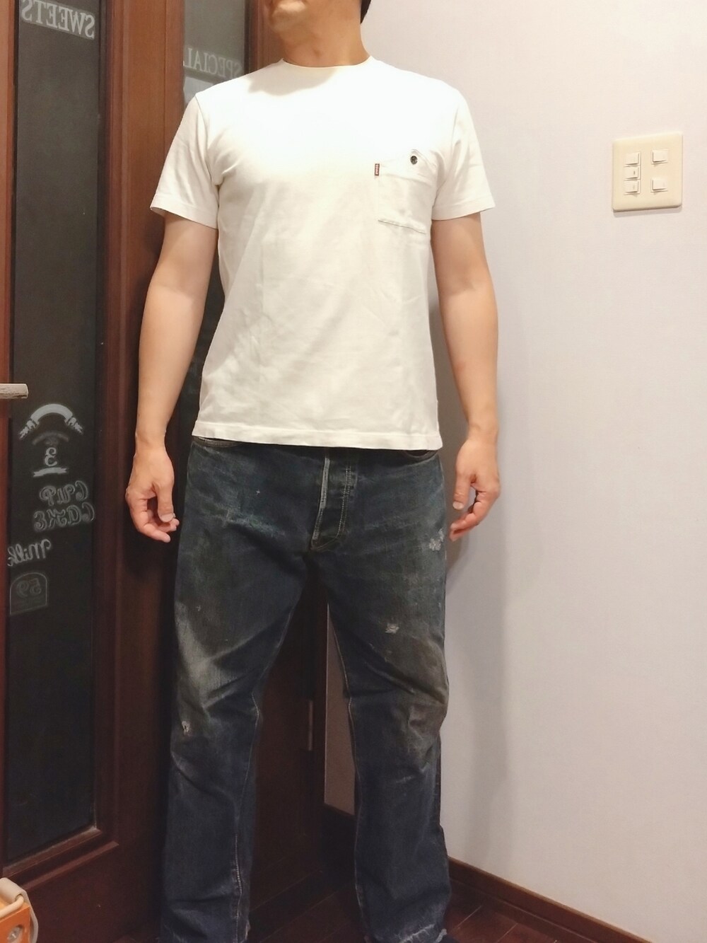 ブルー系のデニムパンツ、ブラック系のニット/セーター、ホワイト系のTシャツ/カットソーを着用したメンズの秋コーディネートの3枚目の写真