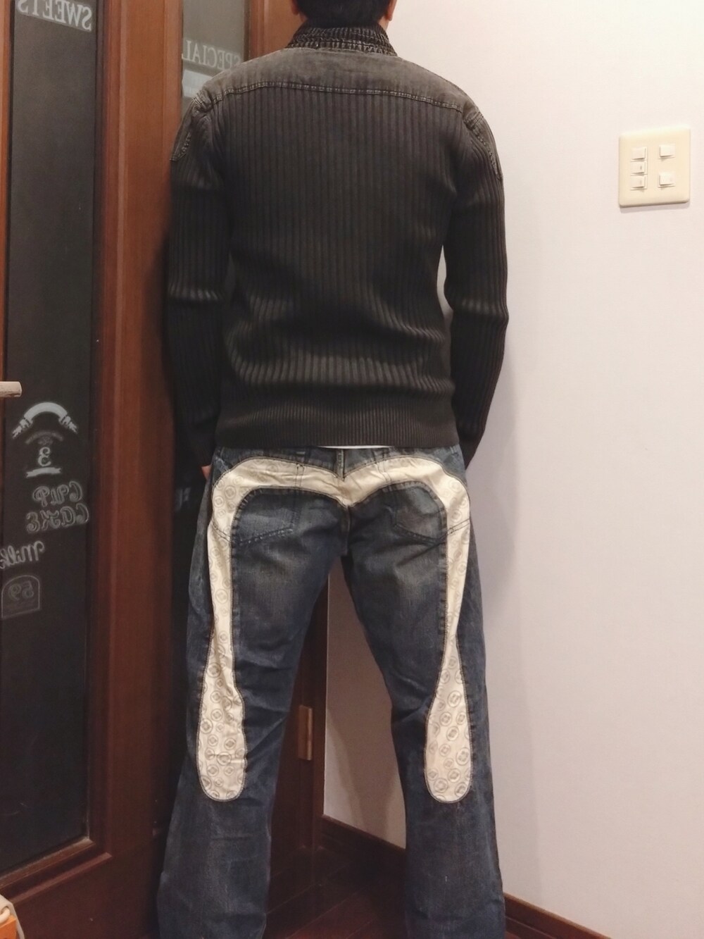 ブルー系のデニムパンツ、ブラック系のニット/セーター、ホワイト系のTシャツ/カットソーを着用したメンズの秋コーディネートの2枚目の写真