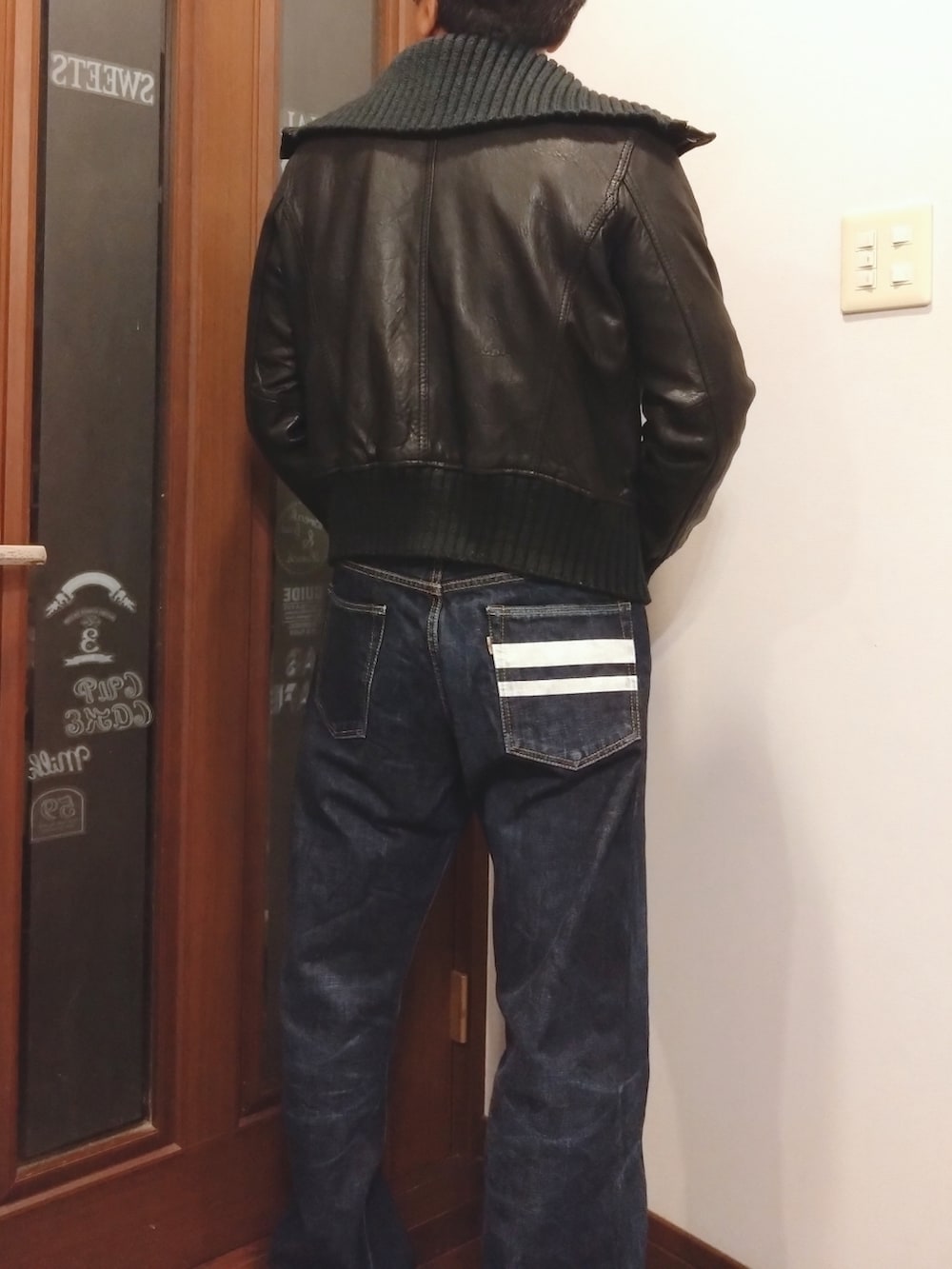 ブラック系のブルゾン、ベージュ系のシャツ/ブラウス、ブルー系のデニムパンツを着用したメンズの秋コーディネートの2枚目の写真