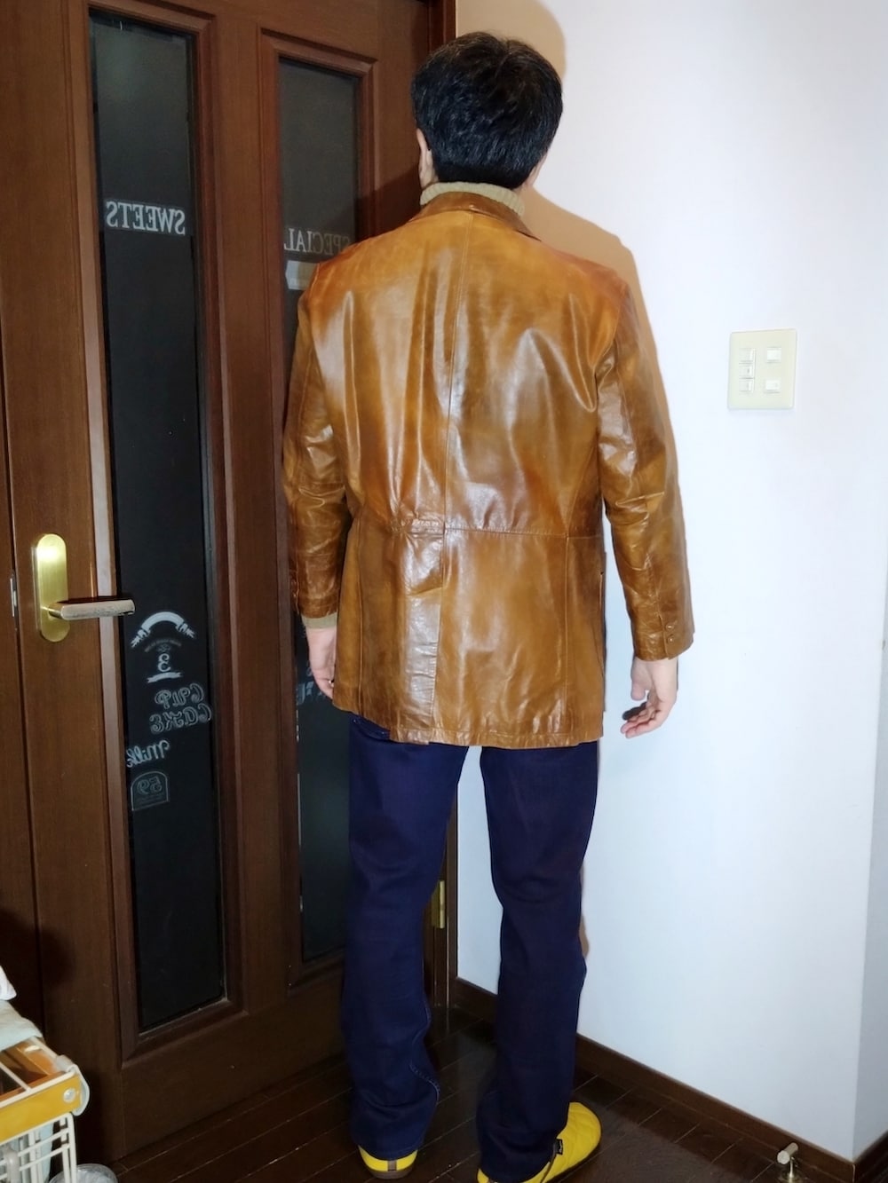 パープル系のデニムパンツ、ベージュ系のニット/セーター、ブラウン系のテーラードジャケットを着用したメンズの冬コーディネートの2枚目の写真