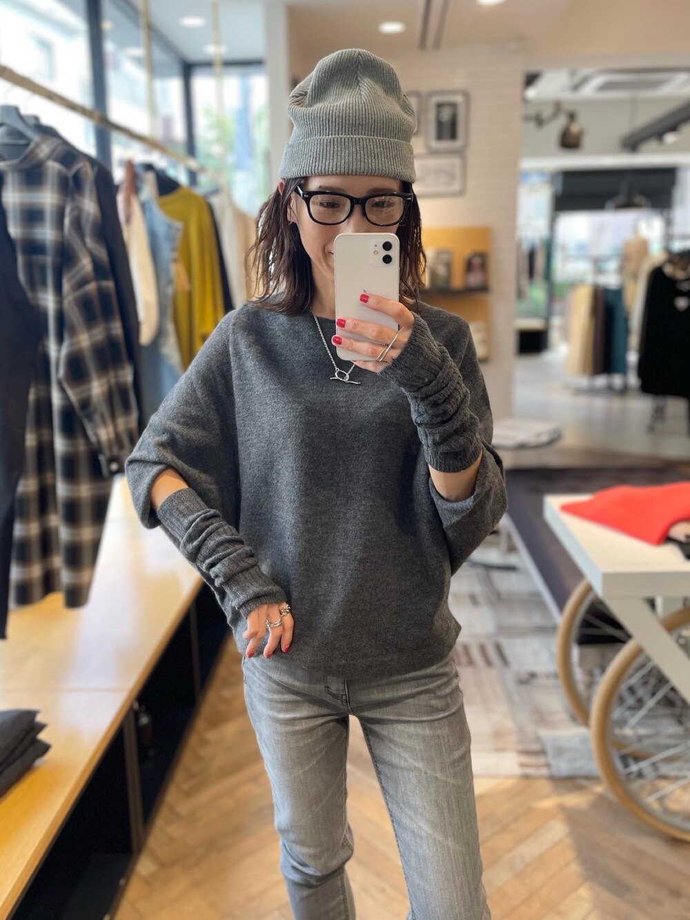 グレー系のニット/セーター、グレー系のデニムパンツ、ブラック系のブーツを着用したレディースの秋コーディネートの2枚目の写真