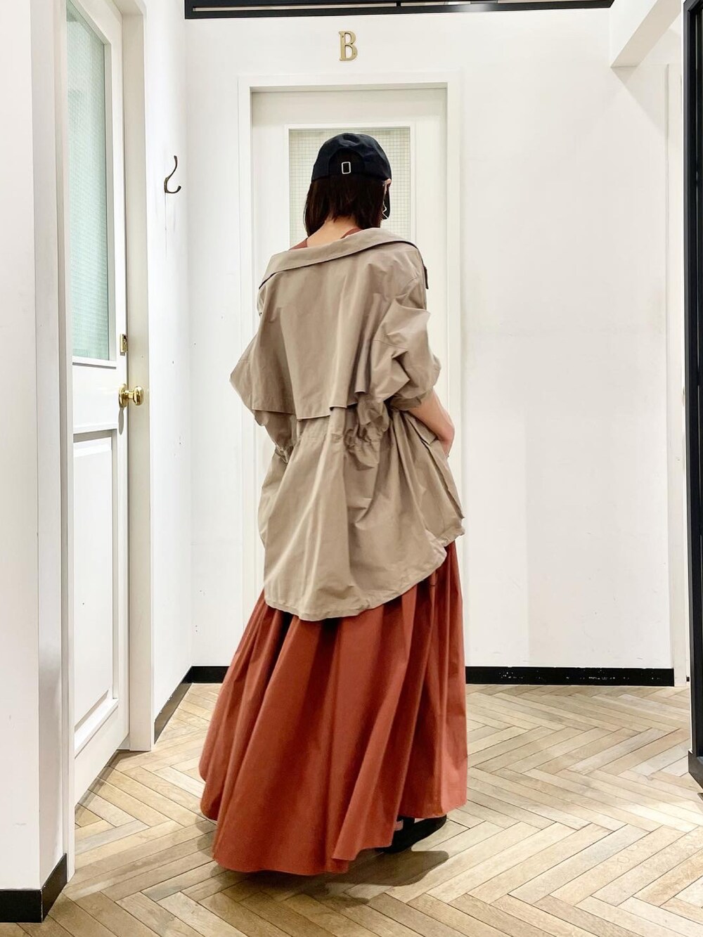 レッド系のワンピース、ブラック系のサンダル、ベージュ系のジャケット/アウターを着用したレディースの春コーディネートの2枚目の写真