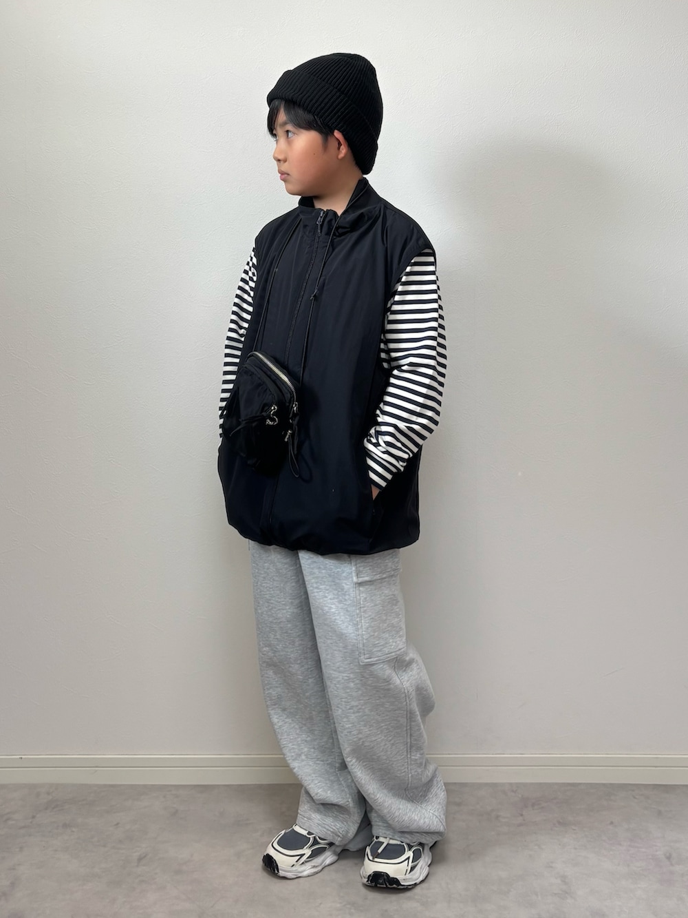 ブラック系のベスト、グレー系のスウェットパンツ、ブラック系のショルダーバッグを着用したキッズの秋コーディネートの2枚目の写真