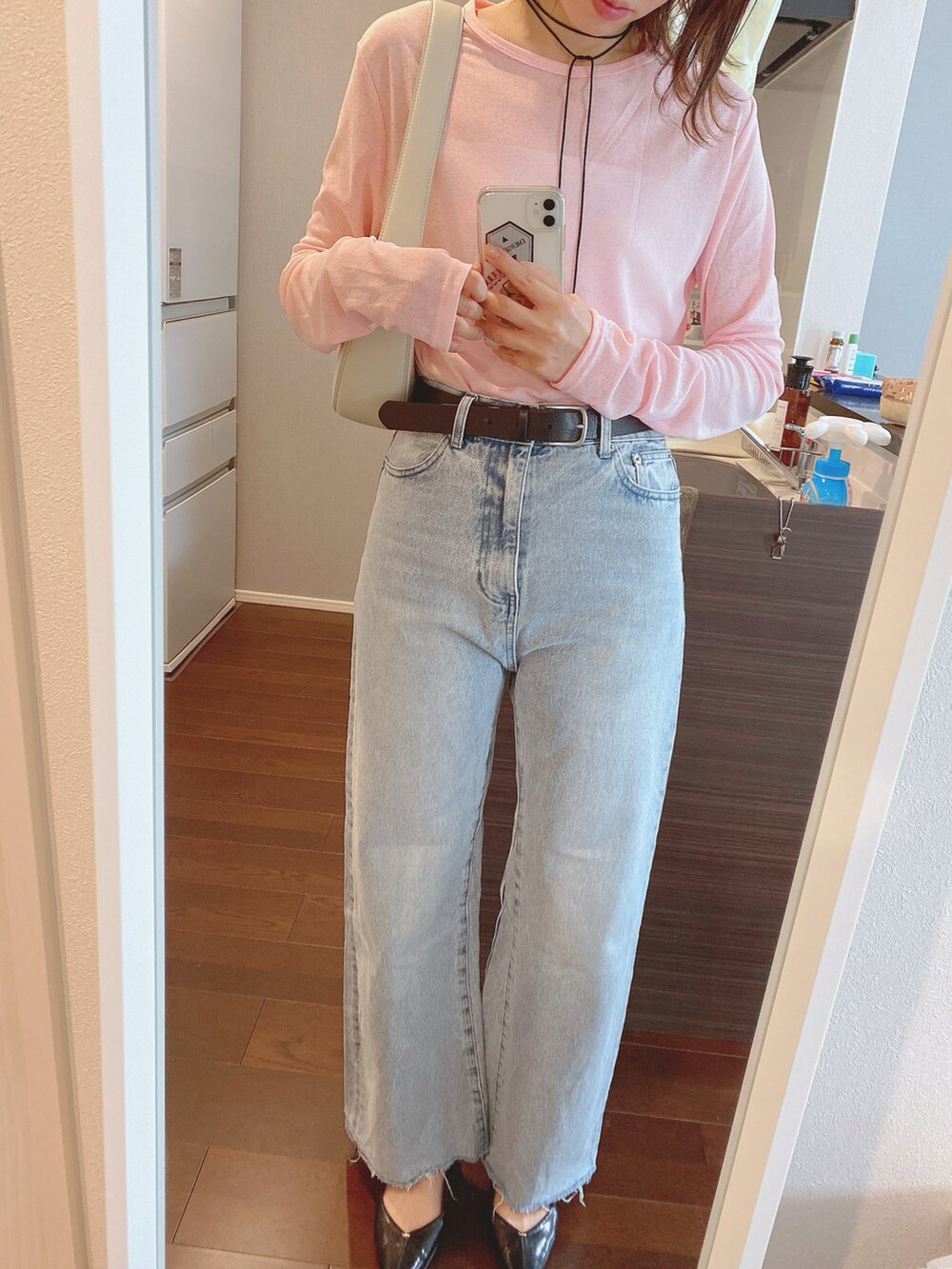 ブルー系のデニムパンツ、ホワイト系のショルダーバッグ、ブラック系のパンプスを着用したレディースの春コーディネートの2枚目の写真