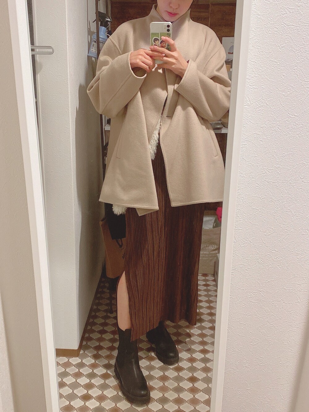 ホワイト系のベスト、ブラウン系のスカート、ブラック系のブーツを着用したレディースの冬コーディネートの2枚目の写真