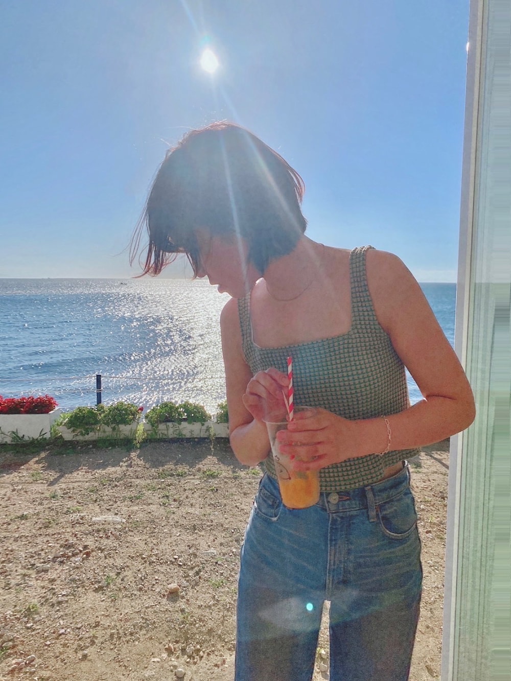 ベージュ系のタンクトップ、ブルー系のデニムパンツを着用したレディースの夏コーディネートの3枚目の写真