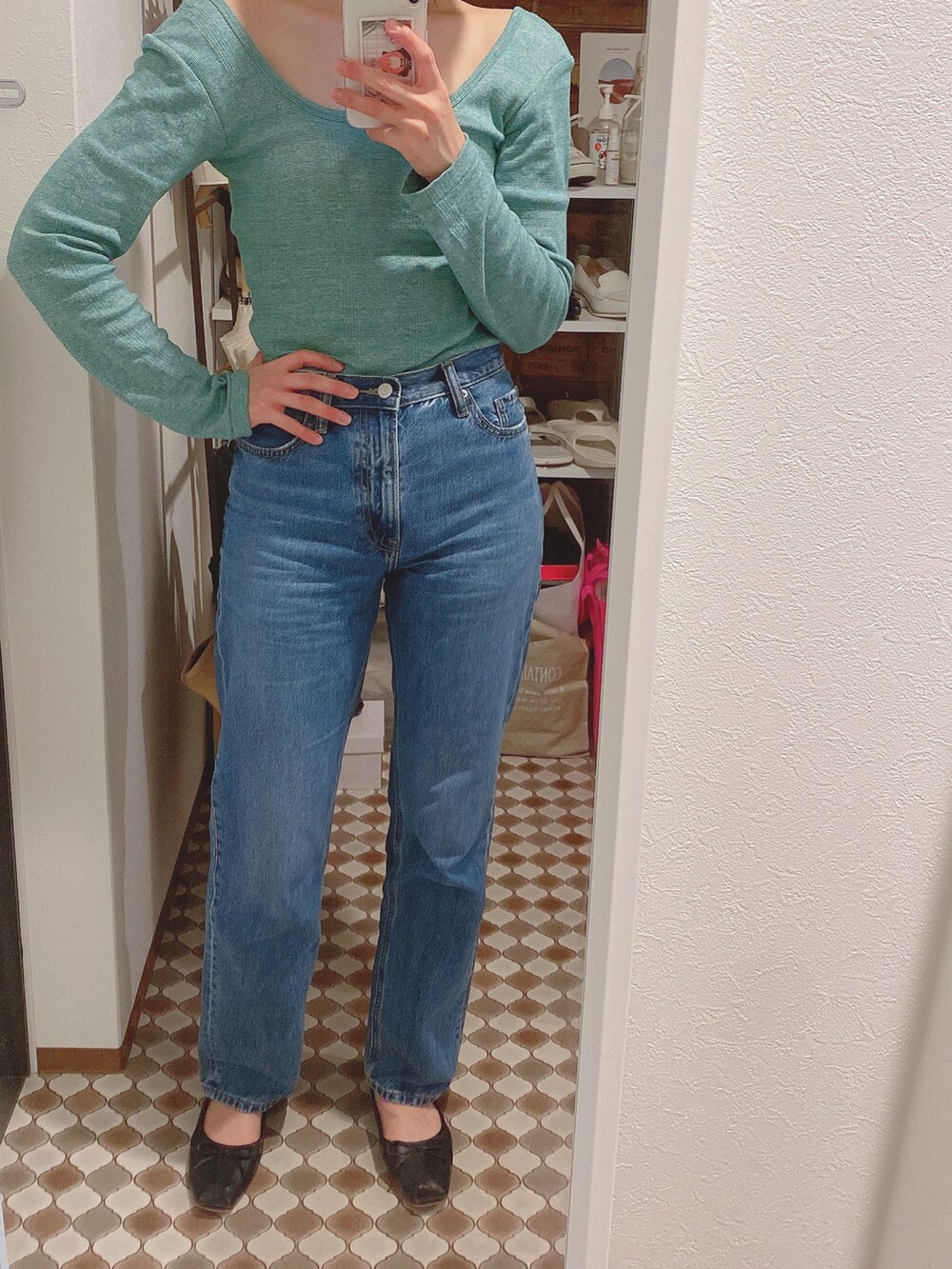 ブルー系のデニムパンツ、ブラック系のバレエシューズ、グリーン系のTシャツ/カットソーを着用したレディースの春コーディネートの2枚目の写真