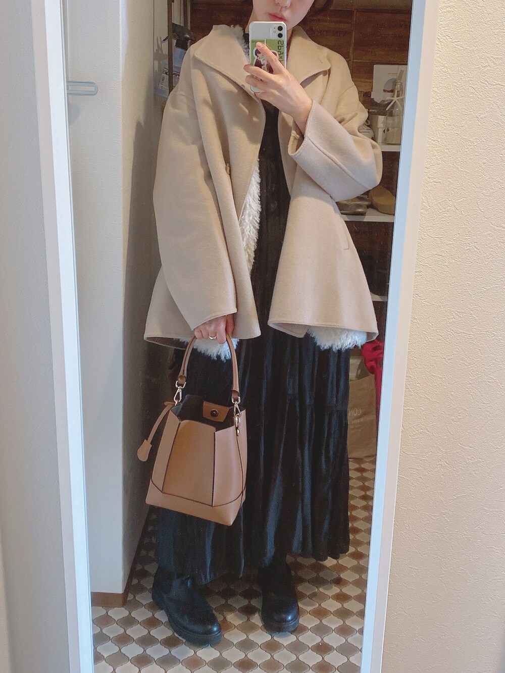 ホワイト系のベスト、ブラック系のドレス、ブラック系のブーツを着用したレディースの冬コーディネートの3枚目の写真