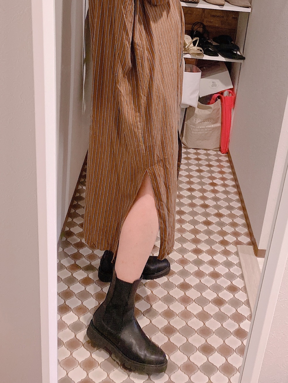 ブラウン系のシャツワンピース、ブラック系のブーツを着用したレディースの秋コーディネートの3枚目の写真