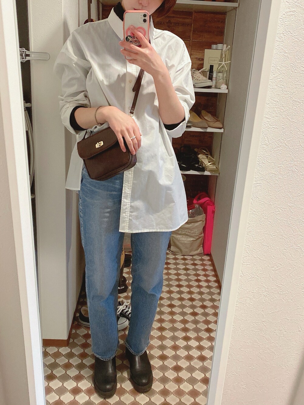 ブルー系のデニムパンツ、ブラック系のブーツ、ブラウン系のショルダーバッグを着用したレディースの冬コーディネートの2枚目の写真