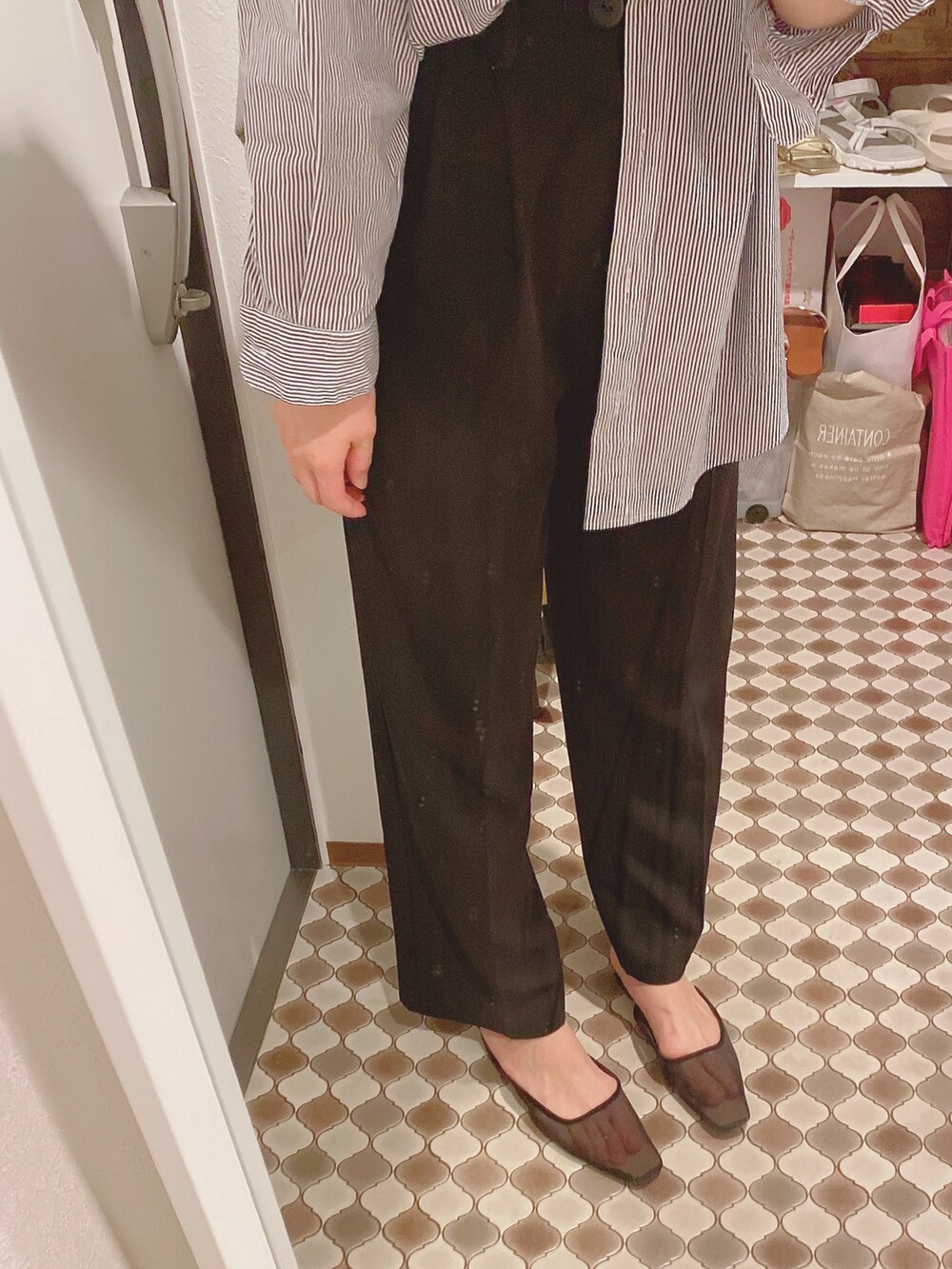 ブラック系のスラックス、ブラック系のパンプス、ブルー系のシャツ/ブラウスを着用したレディースの春コーディネートの2枚目の写真