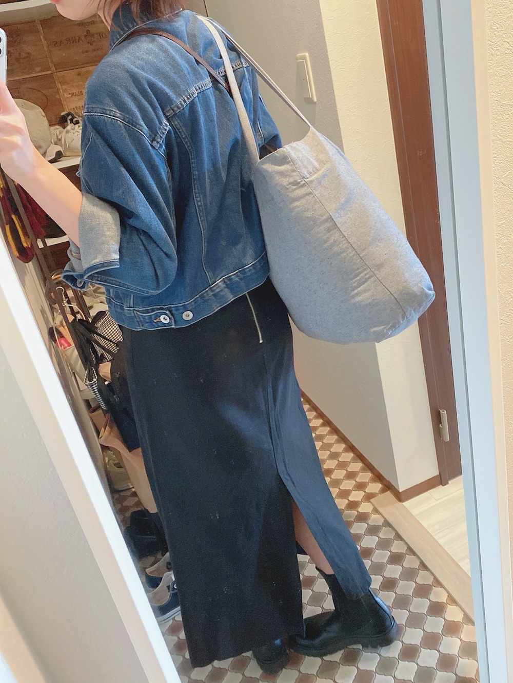 ブルー系のデニムジャケット、ブラック系のスカート、ブラック系のブーツを着用したレディースの春コーディネートの2枚目の写真