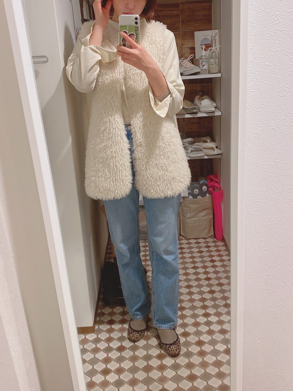 ホワイト系のベスト、ブルー系のデニムパンツ、その他のバレエシューズを着用したレディースの冬コーディネートの2枚目の写真