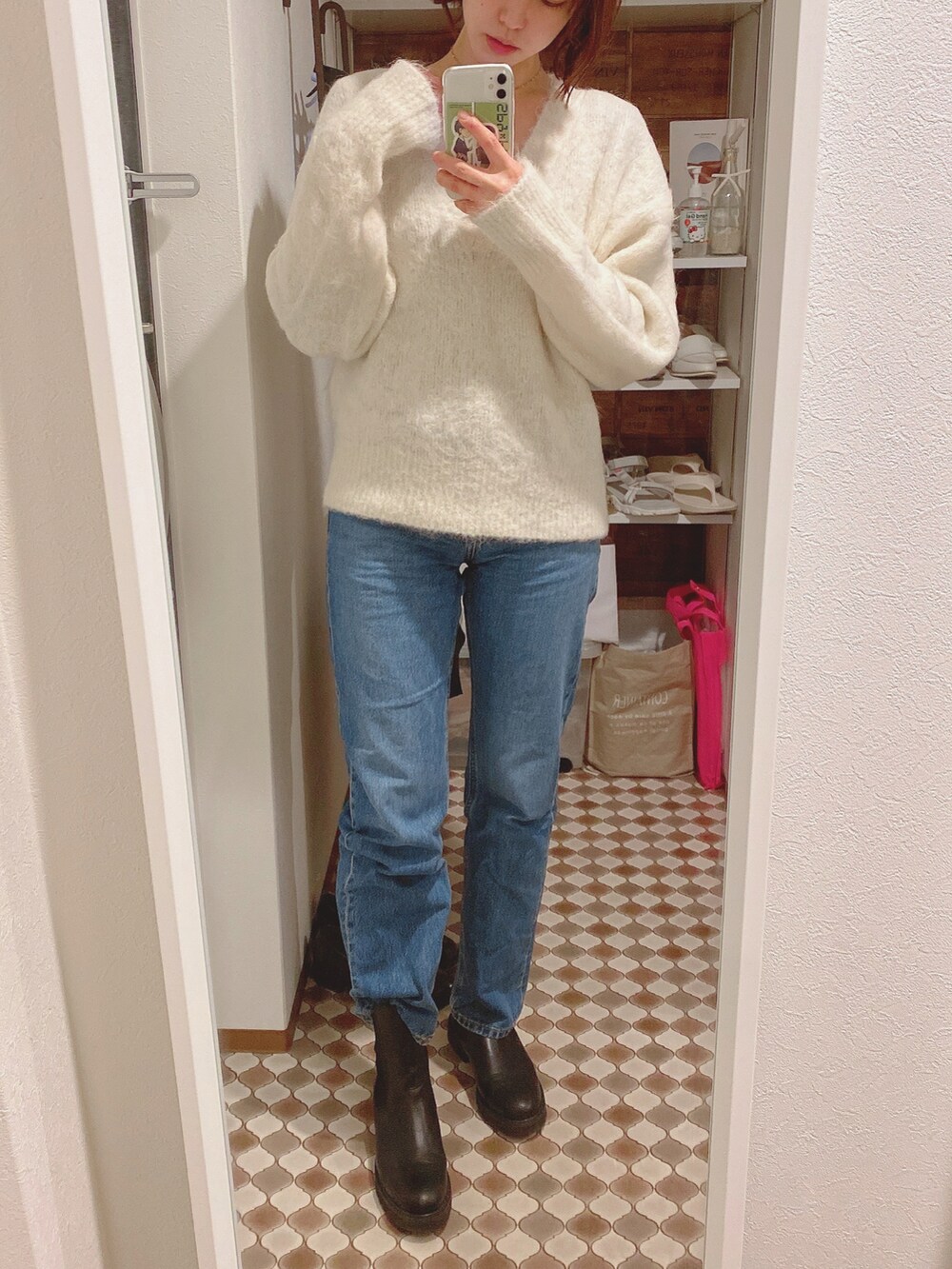 ブルー系のデニムパンツ、ホワイト系のニット/セーター、ホワイト系のダウンジャケット/コートを着用したレディースの冬コーディネートの3枚目の写真