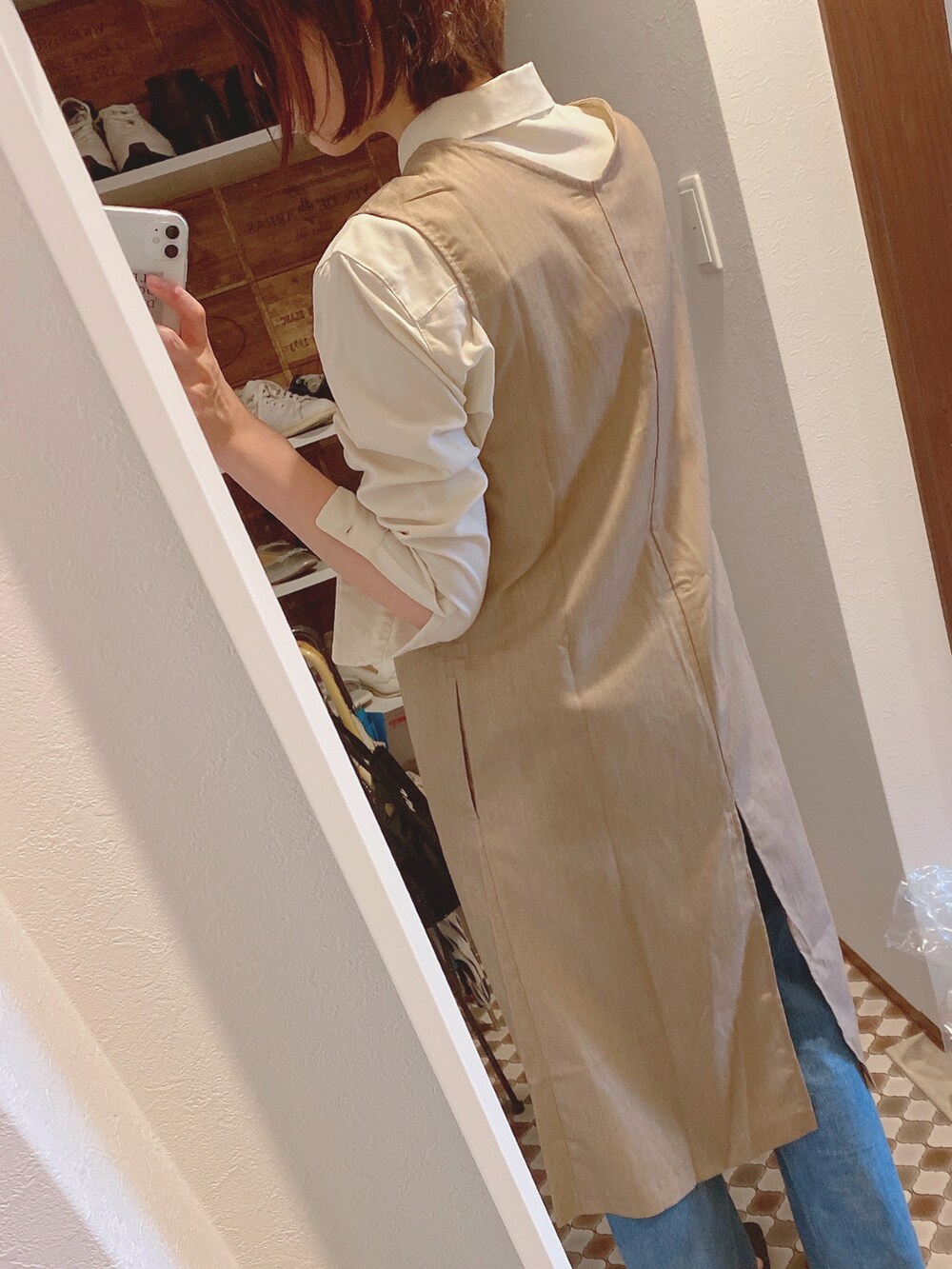 ベージュ系のベスト、ブルー系のデニムパンツ、ブラック系のパンプスを着用したレディースの春コーディネートの3枚目の写真