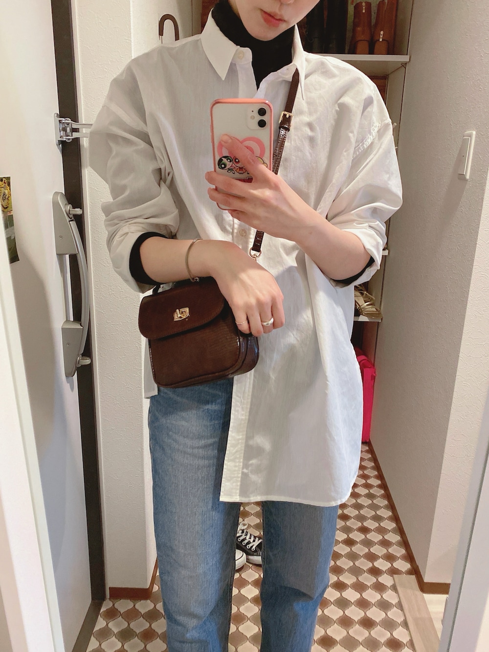 ブルー系のデニムパンツ、ブラック系のブーツ、ブラウン系のショルダーバッグを着用したレディースの冬コーディネートの3枚目の写真