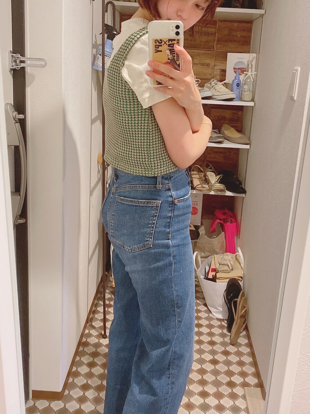 ブルー系のデニムパンツ、ホワイト系のサンダル、ベージュ系のタンクトップを着用したレディースの夏コーディネートの2枚目の写真