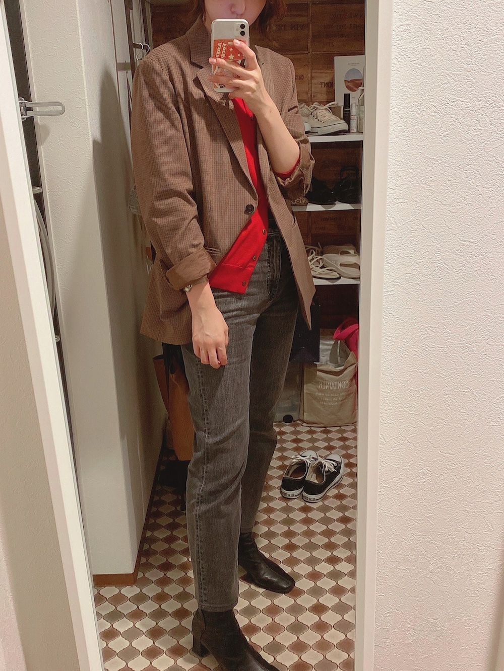 レッド系のカーディガン/ボレロ、ブラウン系のテーラードジャケット、グレー系のデニムパンツを着用したレディースの秋コーディネートの2枚目の写真