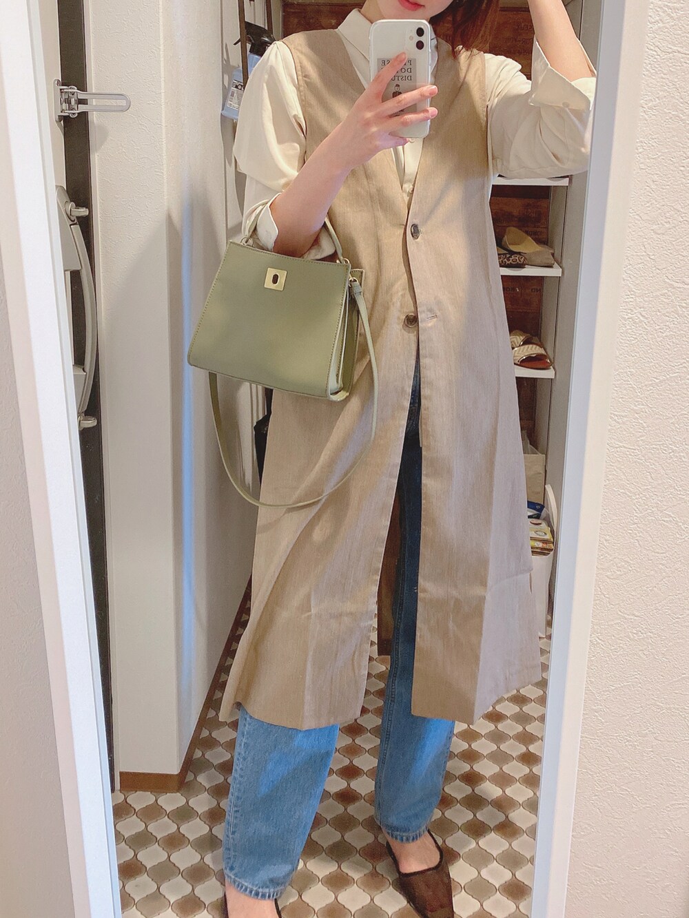 ベージュ系のベスト、ブルー系のデニムパンツ、ブラック系のパンプスを着用したレディースの春コーディネートの4枚目の写真