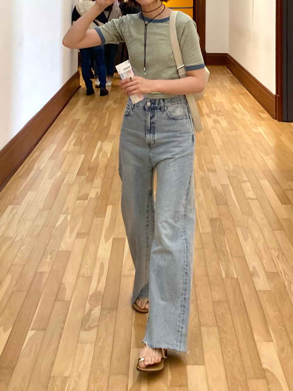 ブルー系のデニムパンツ、イエロー系のサンダル、グリーン系のTシャツ/カットソーを着用したレディースの春コーディネートの4枚目の写真