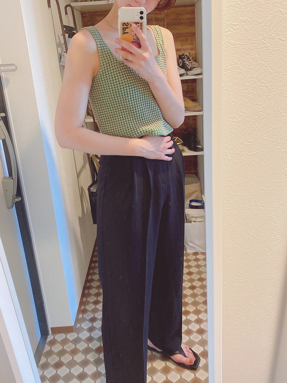 ブラック系のスラックス、ブラック系のサンダル、ベージュ系のタンクトップを着用したレディースの夏コーディネートの2枚目の写真