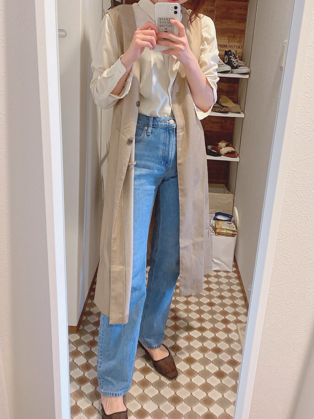 ベージュ系のベスト、ブルー系のデニムパンツ、ブラック系のパンプスを着用したレディースの春コーディネートの2枚目の写真