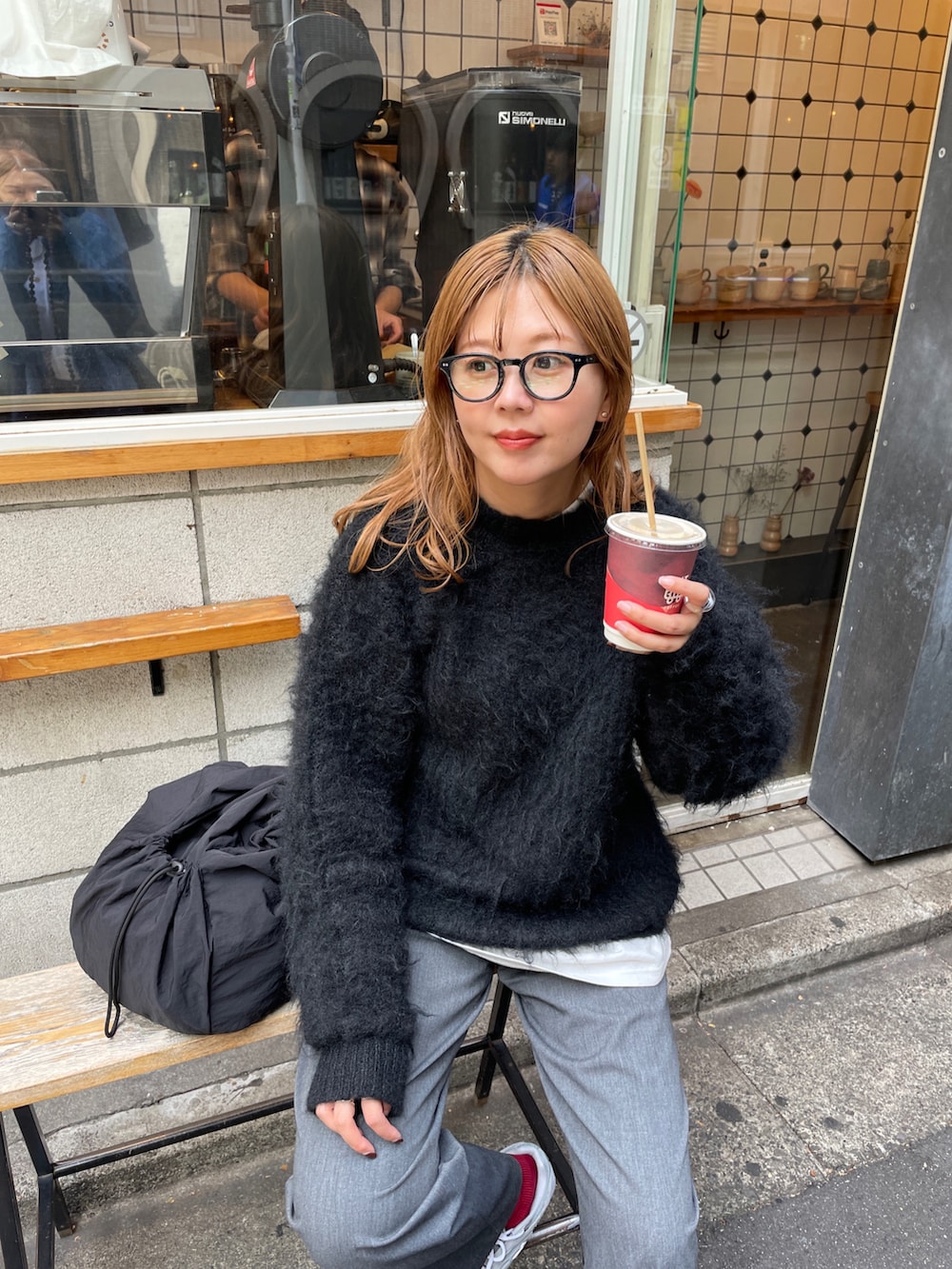 グレー系のスニーカー、ブラック系のバックパック/リュック、ブラック系のニット/セーターを着用したレディースの秋コーディネートの4枚目の写真