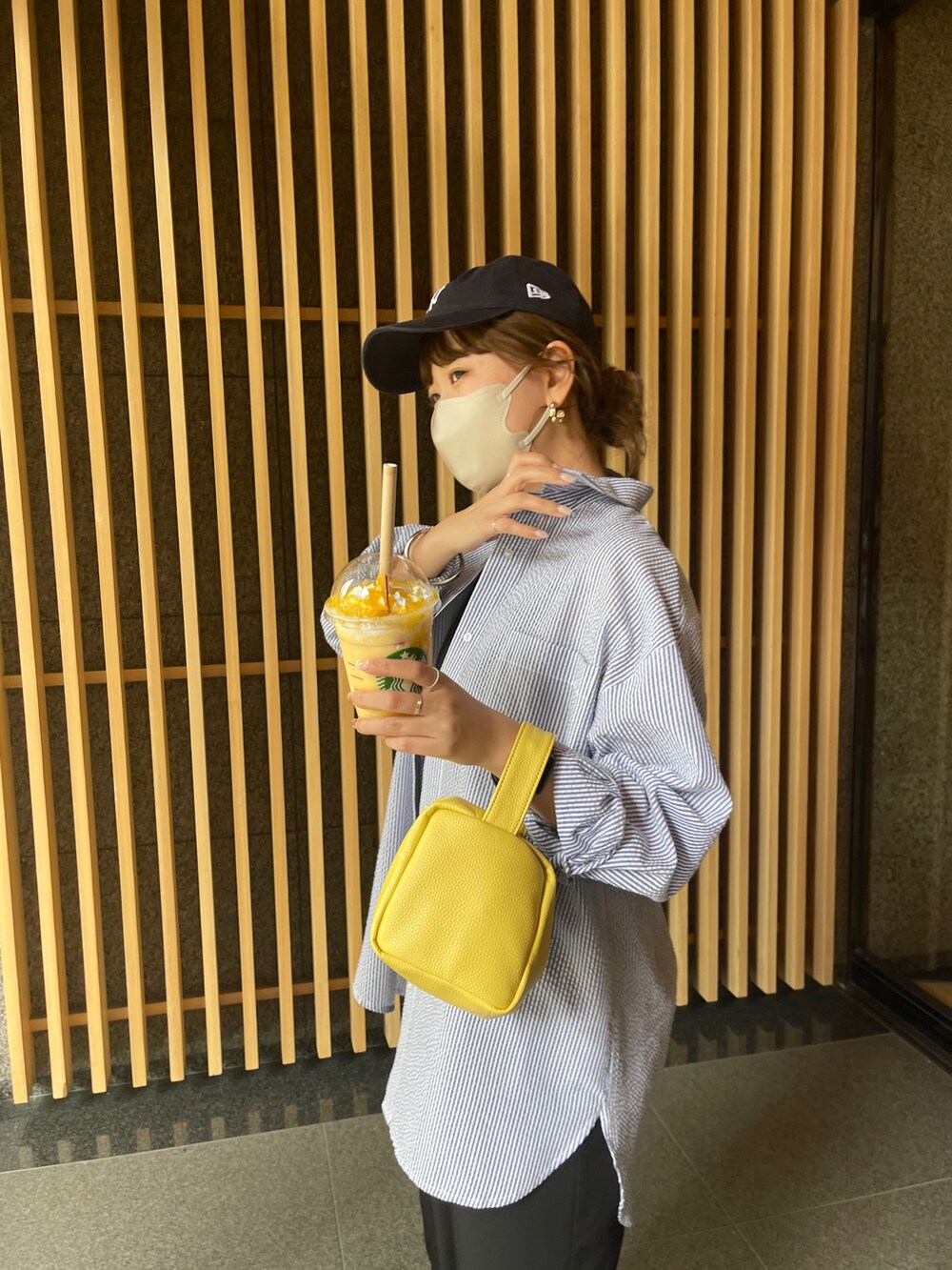 ブラック系のワンピース、ブラック系のサンダル、イエロー系のショルダーバッグを着用したレディースの春コーディネートの2枚目の写真