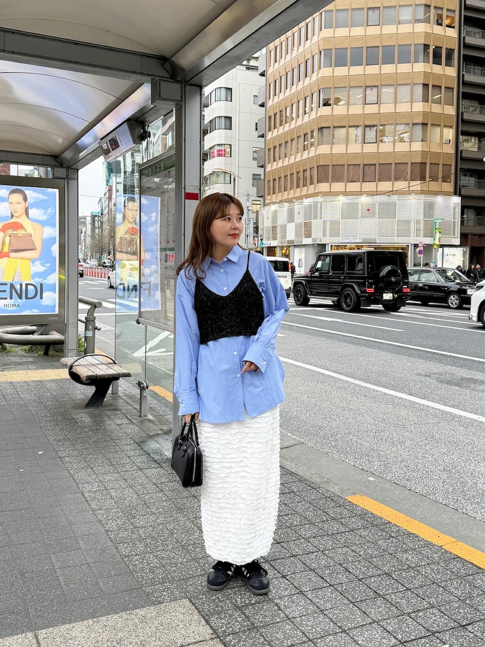 ブラウン系のバッグ、ブラック系のスニーカー、ホワイト系のスカートを着用したレディースの春コーディネートの3枚目の写真