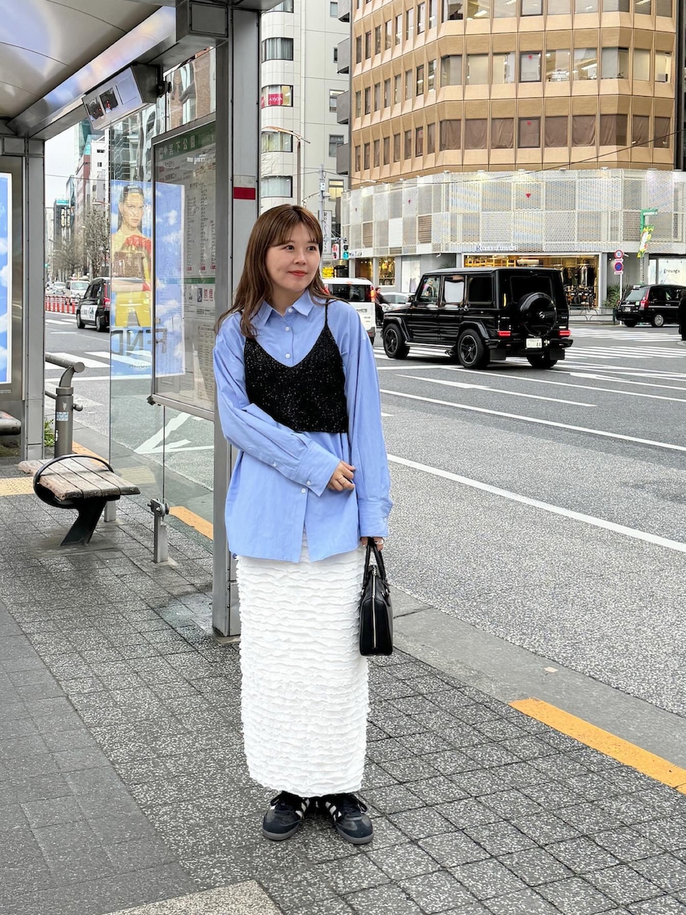 ブラウン系のバッグ、ブラック系のスニーカー、ホワイト系のスカートを着用したレディースの春コーディネートの4枚目の写真