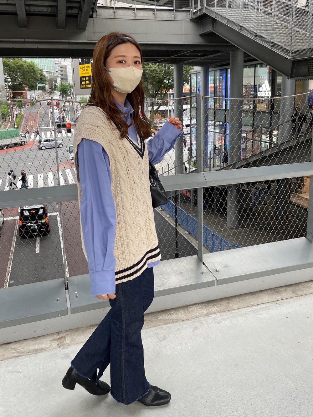 ブルー系のデニムパンツ、ブラック系のショルダーバッグ、ホワイト系のベストを着用したレディースの秋コーディネートの5枚目の写真