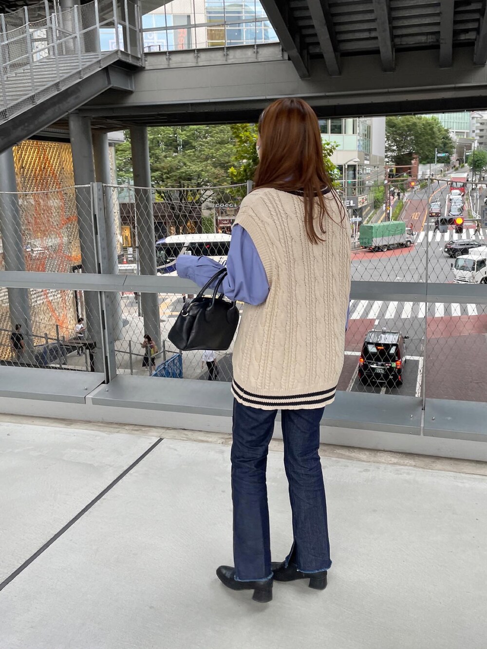 ブルー系のデニムパンツ、ブラック系のショルダーバッグ、ホワイト系のベストを着用したレディースの秋コーディネートの4枚目の写真