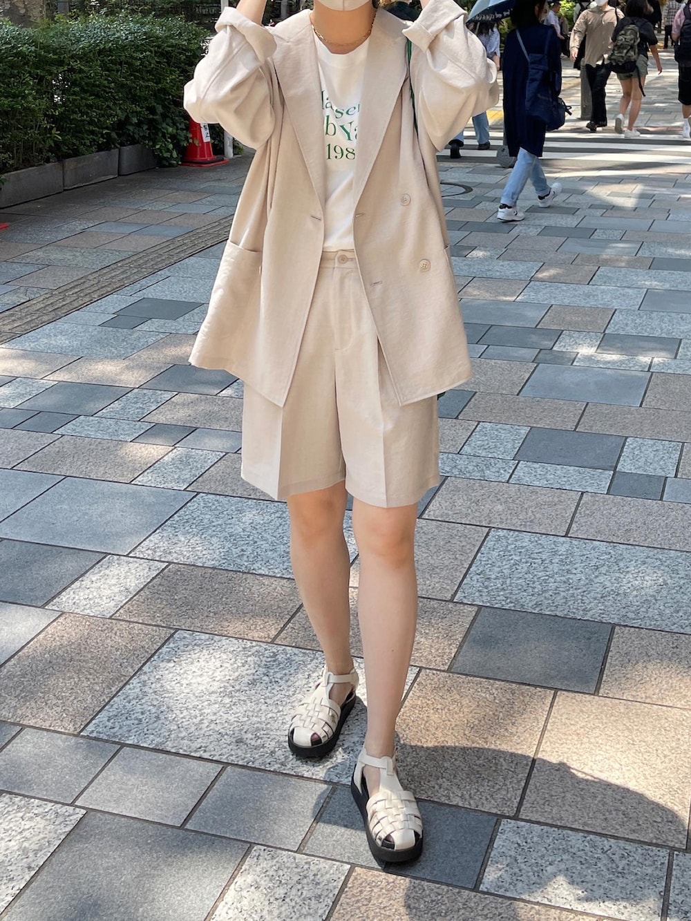 ブラック系のサンダル、オレンジ系のTシャツ/カットソー、ベージュ系のテーラードジャケットを着用したレディースの春コーディネートの5枚目の写真