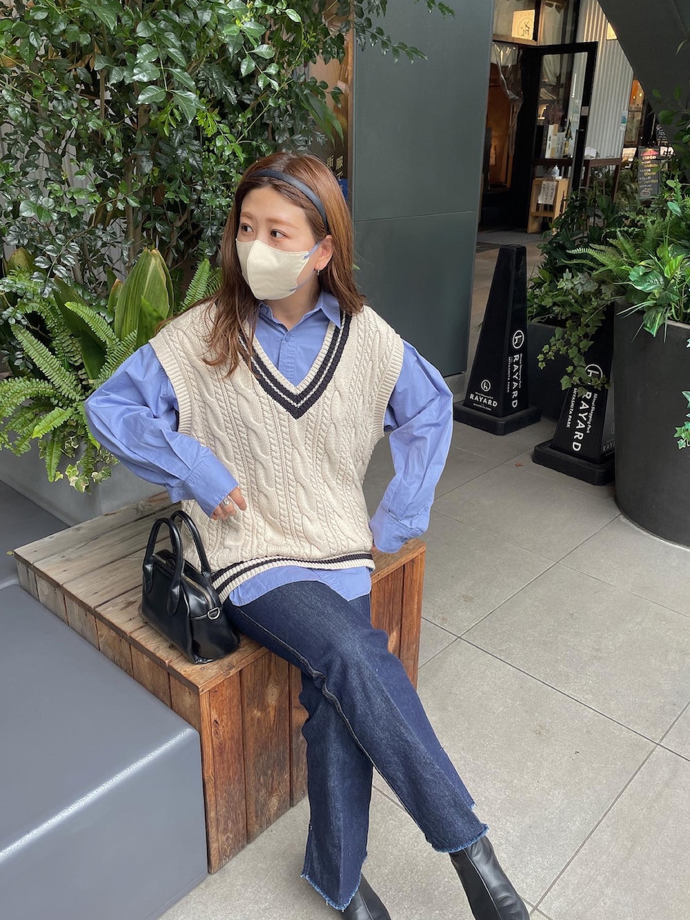 ブルー系のデニムパンツ、ブラック系のショルダーバッグ、ホワイト系のベストを着用したレディースの秋コーディネートの3枚目の写真