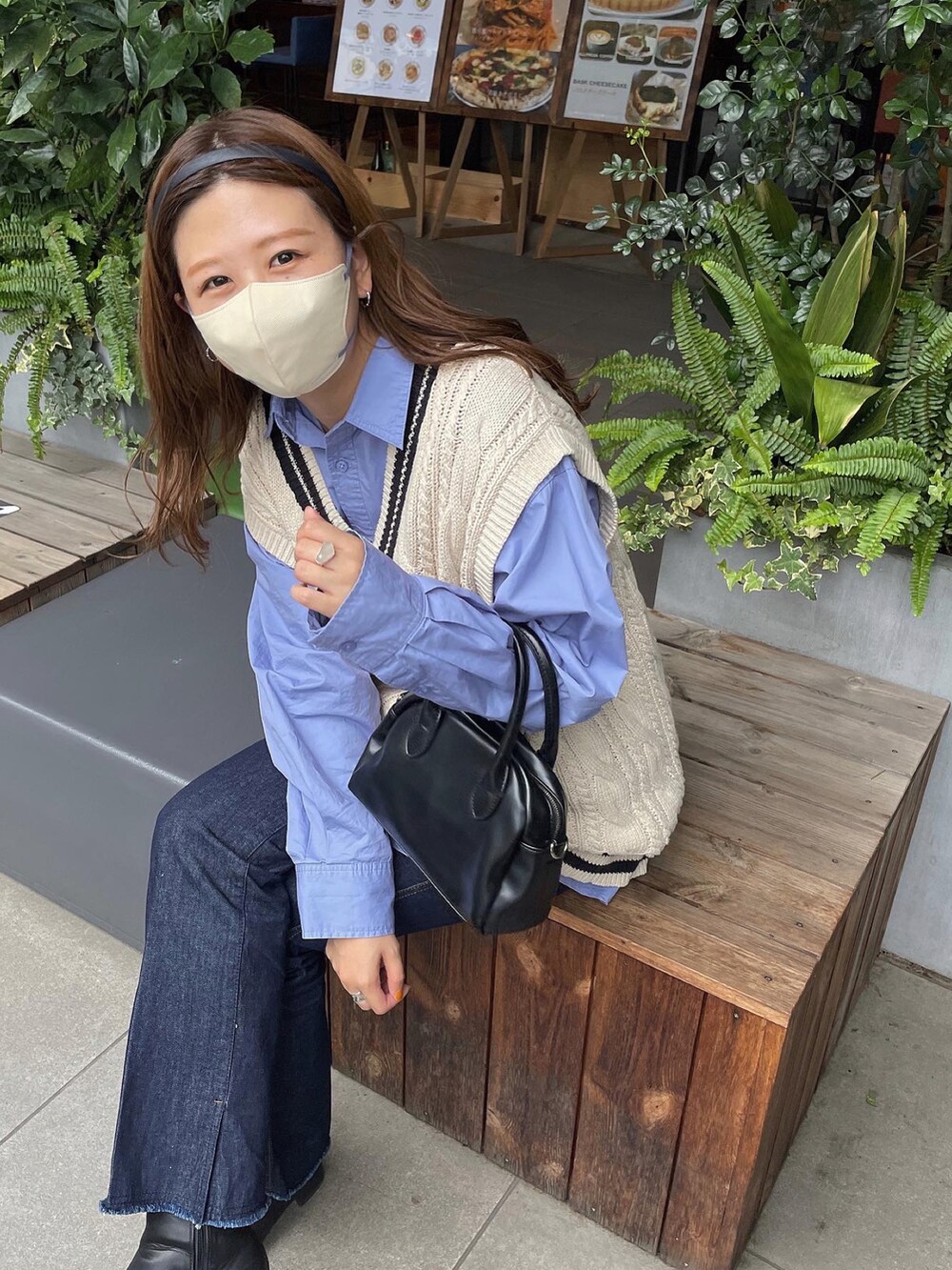 ブルー系のデニムパンツ、ブラック系のショルダーバッグ、ホワイト系のベストを着用したレディースの秋コーディネートの2枚目の写真