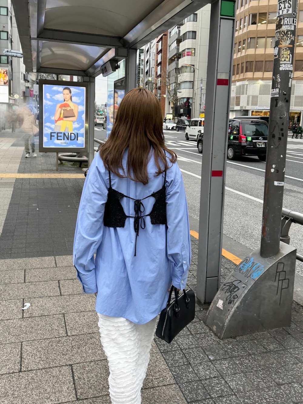 ブラウン系のバッグ、ブラック系のスニーカー、ホワイト系のスカートを着用したレディースの春コーディネートの5枚目の写真