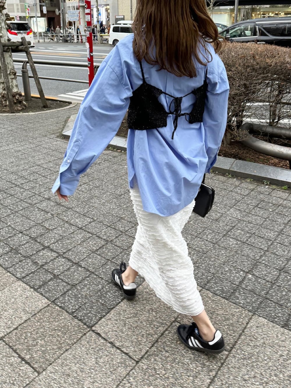 ブラウン系のバッグ、ブラック系のスニーカー、ホワイト系のスカートを着用したレディースの春コーディネートの2枚目の写真